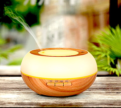The Aromapod nebulizer lit and diffusing mist on a wooden surface